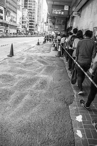 human grayscale photo of group of people lining beside building person