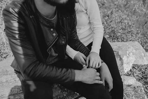 human grayscale photo of man and woman sitting on bench people