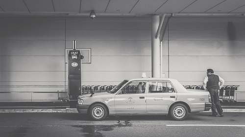 grey grayscale photo of man beside car human