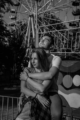 people grayscale photo of man hugging woman near Ferri's wheel human