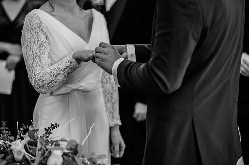 person grayscale photo of man insert ring into woman during wedding ceremony human