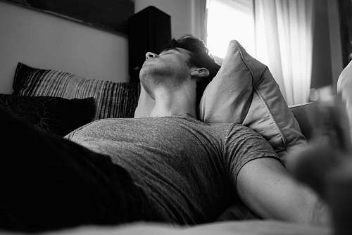 grey grayscale photo of man laying on bed nap