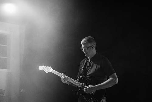 person grayscale photo of man playing guitar people