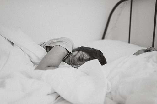 bed grayscale photo of sleeping woman lying on bed furniture