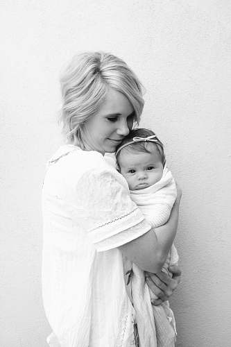 person grayscale photo of woman carrying baby baby