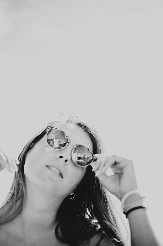 human grayscale photo of woman holding sunglasses person