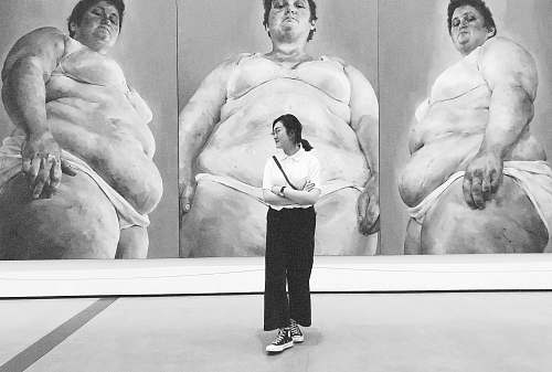 person grayscale photo of woman standing in front of sumo wrestler painting art