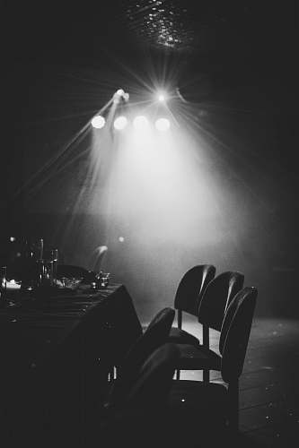 lighting grayscale photography of chairs and table near lights chair