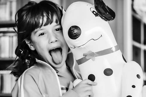 human grayscale photography of girl making silly face while inflatable dalmatian balloon person