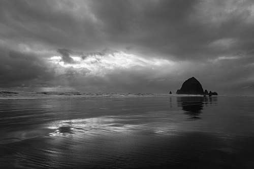 nature grayscale photography of island under clouds weather
