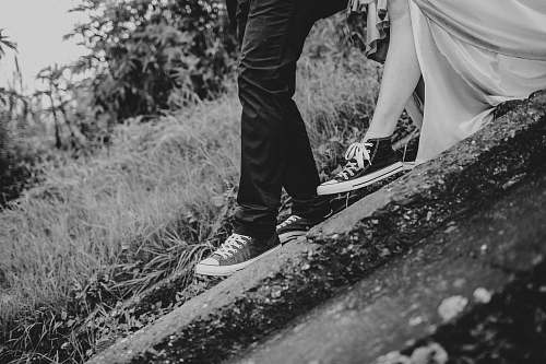 converse grayscale photography of man and woman standing on ground wedding