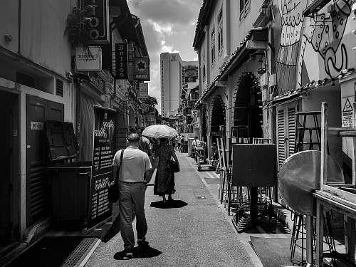 human grayscale photography of man and woman walking along narrow pathway path