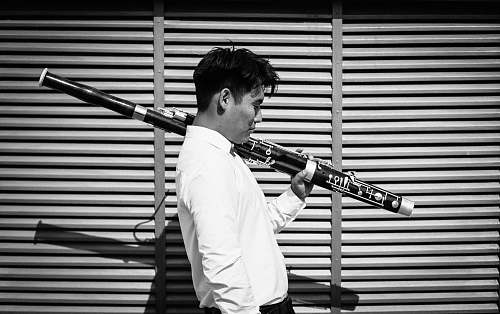 human grayscale photography of man carrying a wind instrument person