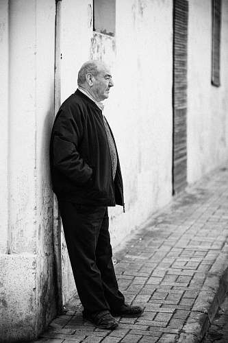 apparel grayscale photography of man leaning against wall clothing