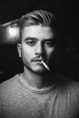 person grayscale photography of man smoking while taking picture people