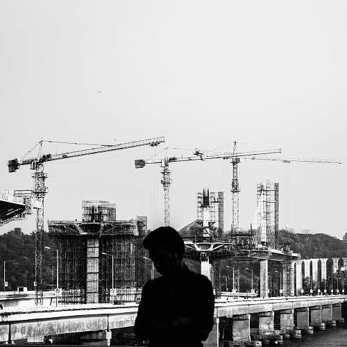 person grayscale photography of man with a construction site in the background human