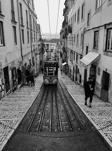 path grayscale photography of tram passing through ascending alley walkway