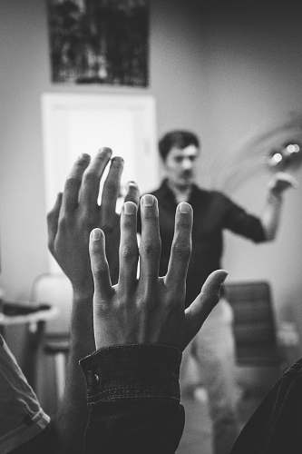person grayscale photography of two people raising their hands finger