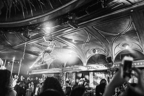 human grayscale photography of woman hanging near ceiling surrounded by crowd person