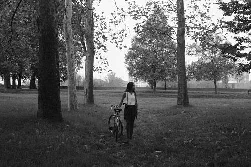 human grayscale photography of woman holding bike bike