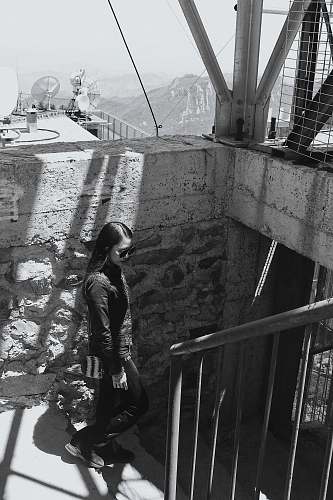 banister grayscale photography of woman in sunglasses standing on staircase handrail