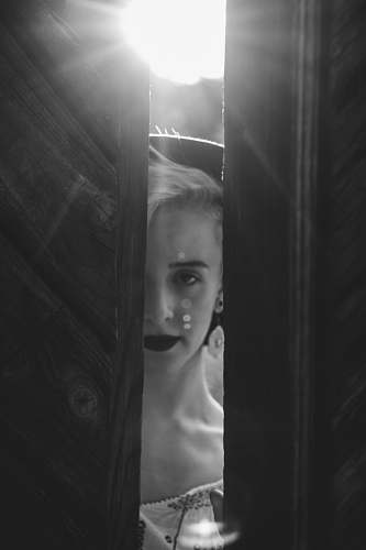 face grayscale photography of woman standing in front of door sibiu
