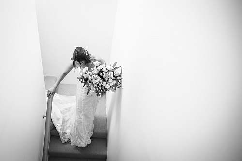 apparel grayscale photography of woman wearing wedding gown walking on steps clothing