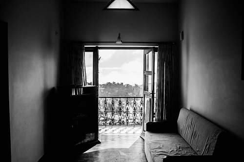 room greyscale photgraphy of fabric sofa beside wall inside the building kodaikanal