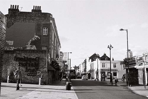 human greyscale photo of buildings path