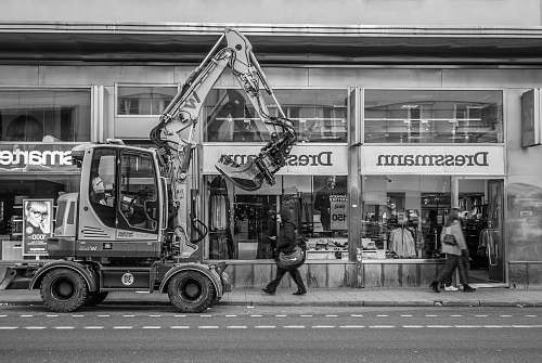 human greyscale photo of excavator beside building person