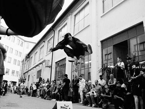 person greyscale photo of man jumping on street people