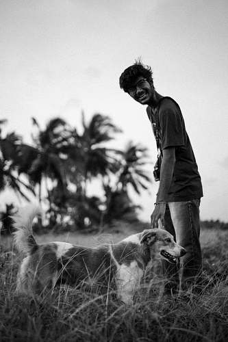 human greyscale photography of man beside dog person
