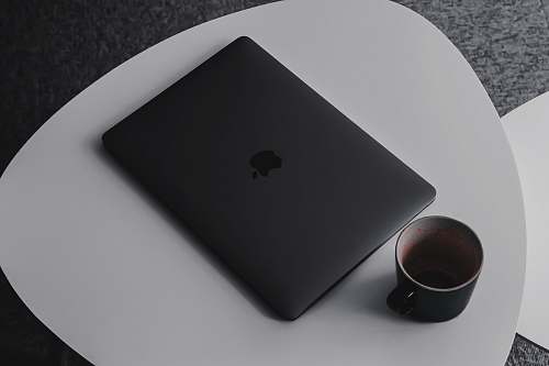 cup MacBook Pro beside mug on table prague