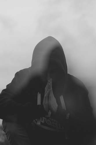 grey man in hoodie sitting against wall apparel