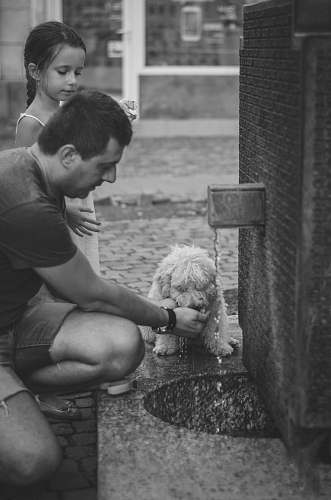 pet man kneeling beside girl feeding dog in grayscale photograpy human