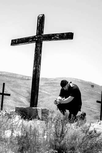 symbol man kneeling in front of wooden cross cross