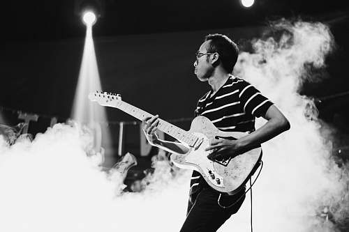 human man playing guitar on stage with smoke person