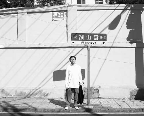 apparel man standing near street post grayscale photo clothing