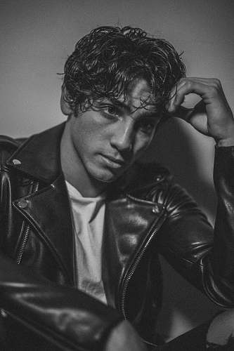 clothing man wearing leather jacket resting head on hand apparel