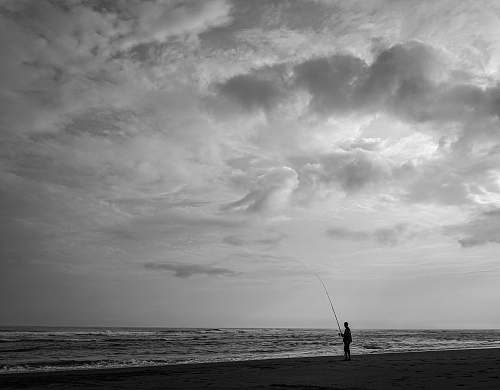 person person fishing on body of water grey