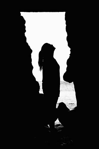 person silhouette of woman looking up inside cave silhouette
