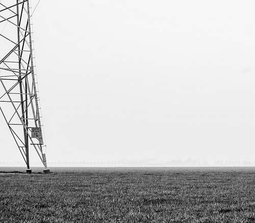 white steel transmission tower on grass plains field