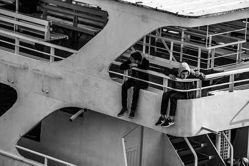 banister two men sitting on yatch handrail