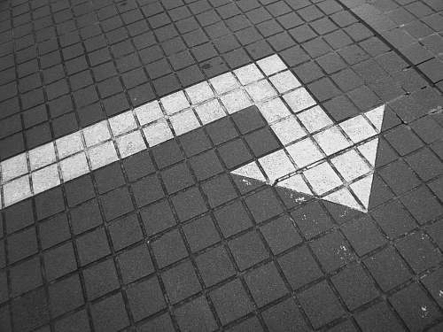 grey white arrow on bricked pavement flooring