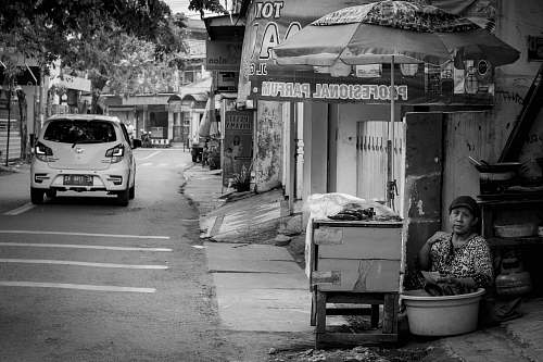 automobile woman sitting by food stall in grayscale photography car