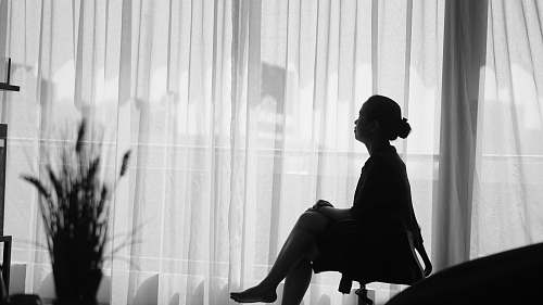 person woman sitting on office rolling armchair beside window plant