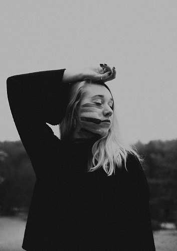 person woman wearing long-sleeved shirt standing grayscale photography face