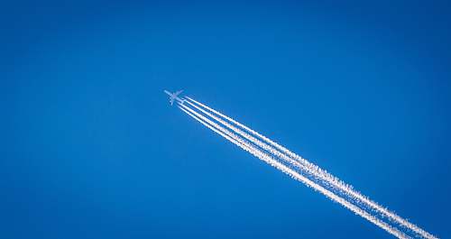contrail white airplane flying under the blue sky sky