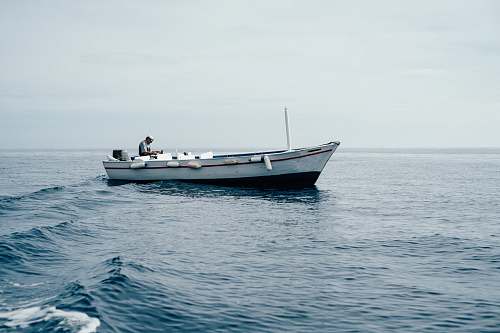 dinghy man sitting on boar in ocean ocean