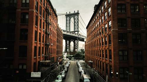 city cars parked on both sides of street near bridge dumbo